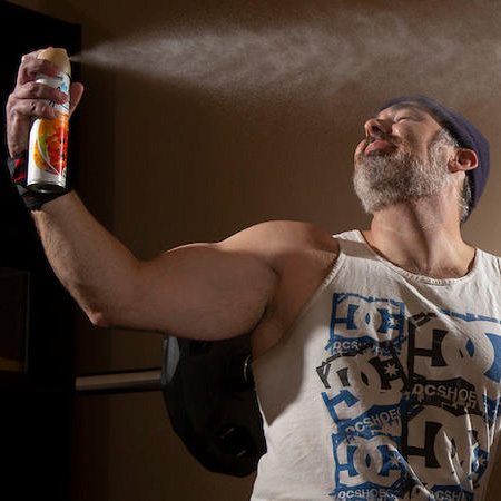 Man in workout gears sprays scented aersol on himself