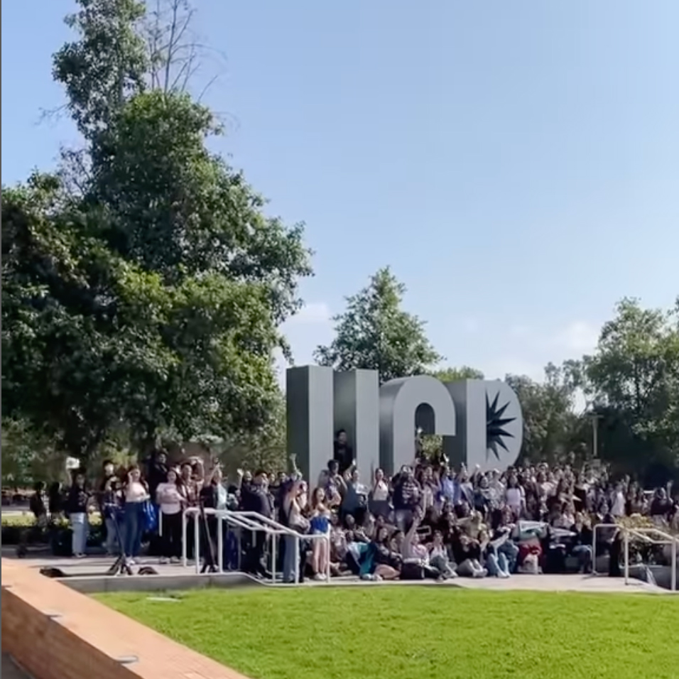 A group of more than 50 students pose  for a group photo in front of the UCR letter sculpture in the heart of the UC Riverside campus.