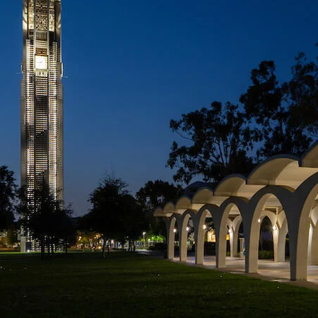 A view of the Bell Tower and Rivera Library arches lit up at night time on the UC Riverside campus.