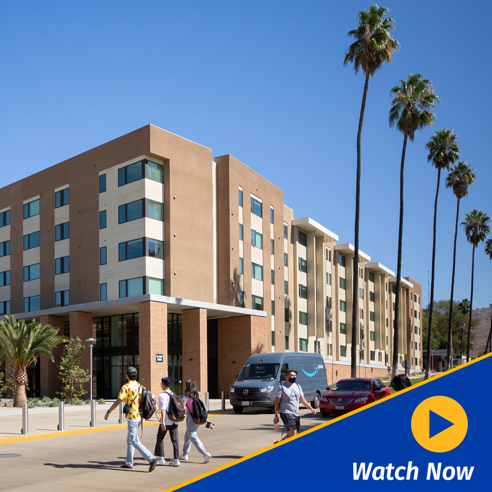 A graphic of a gold video play button with the words 'Watch Now' appear in the lower right corner of a scene of students walking toward the North Distric, UCR's new apartment community.