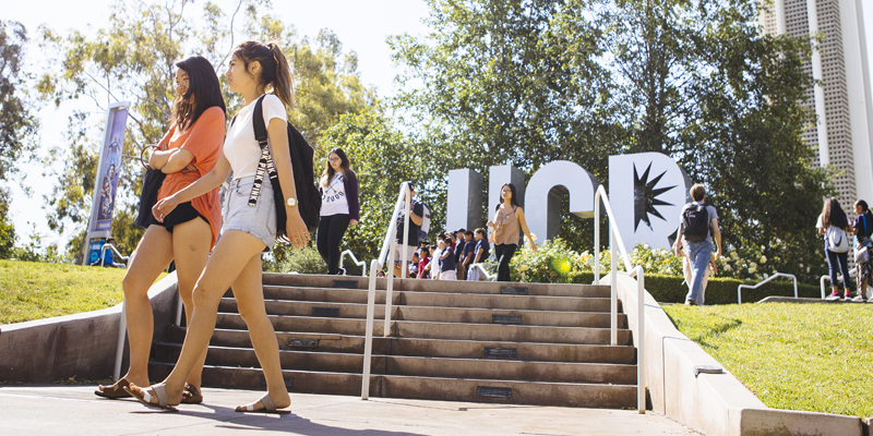 Two female students walk near the UCR lettes monument near the HUB.