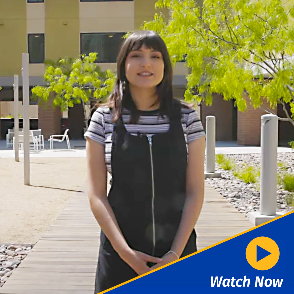 A graphic of a gold video play button with the words 'Watch Now' appear in the lower right corner of a still of a student hosting a tour of UCR housing. 